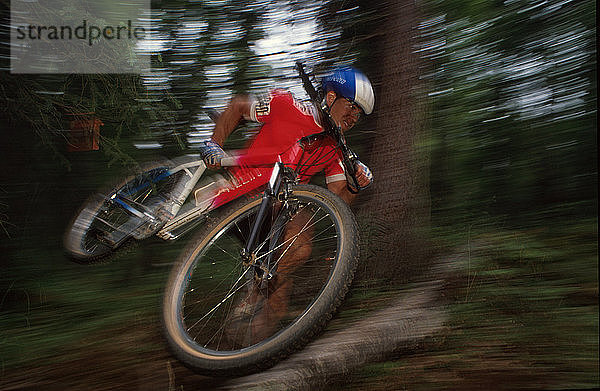 Mountainbiker trägt Fahrrad über Baumhindernisrennen