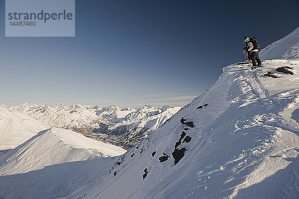 Zwei Skitourengeher spähen über die Kante  um ihr Ziel am Hatcher Pass in Süd-Zentral-Alaska auszukundschaften