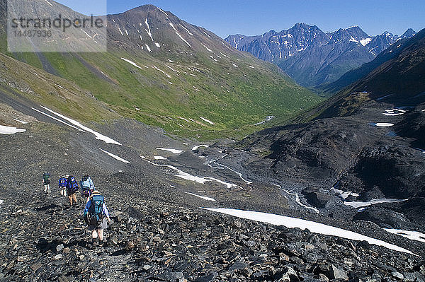 Eine Gruppe von Rucksacktouristen macht sich auf den Weg bergab vom Raven Glacier in Crow Pass  Chugach State Park  Southcentral Alaska  Sommer