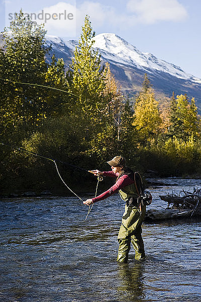 Frau wirft beim Fliegenfischen am Ptarmigan Creek auf der Kenai-Halbinsel in Süd-Zentral-Alaska im Herbst Regenbogenforellen aus
