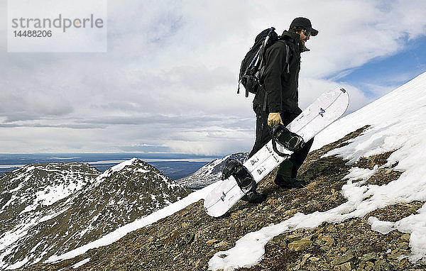 Ein Backcountry-Snowboarder wandert auf den Gipfel von Peak 3 in der Nähe von Anchorage  Alaska