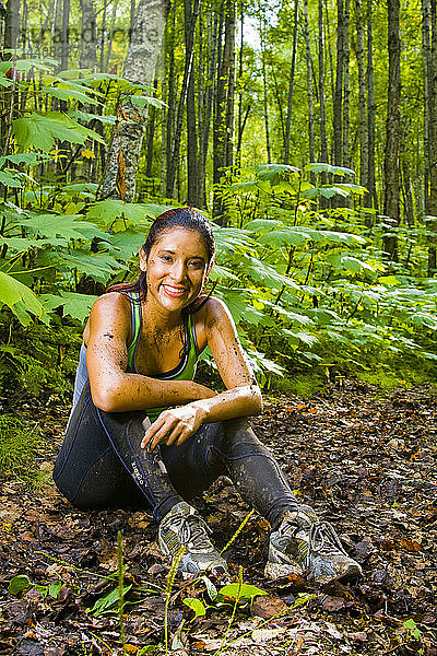 Junge hispanische Frau  die sich nach einem Lauf auf einem schlammigen Weg ausruht  Southcentral Alaska