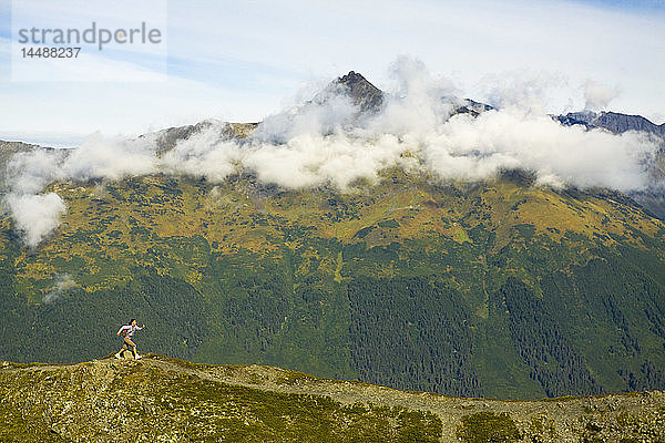 Junge erwachsene hispanische Frau beim Wandern auf dem Gipfel des Berges Alyeska mit Blick auf die Chugach Mountains in der Nähe von Girdwood in Süd-Zentral-Alaska