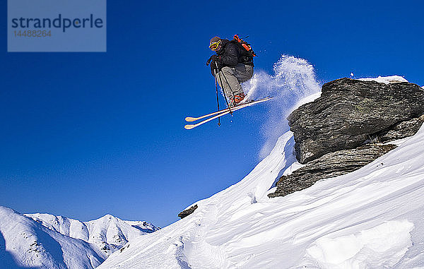 Ein Skifahrer springt von einem Felsen am Hatcher Pass und fährt bergab  Southcentral Alaska