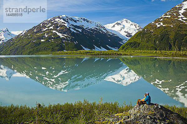 Zwei Wanderer entspannen sich am Portage Lake und genießen den Blick auf den Byron Peak  Portage Valley  Southcentral Alaska im Sommer