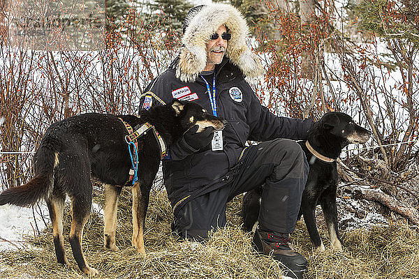 Der freiwillige Tierarzt Jay Butan posiert für Fotos mit abgeworfenen Hunden am Rainy-Pass-Kontrollpunkt während des Iditarod 2014  Southcentral Alaska