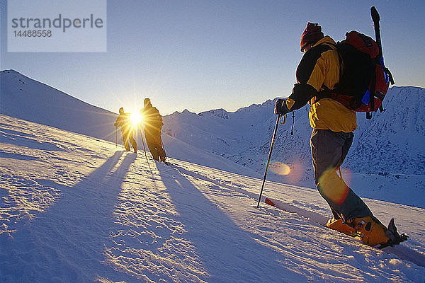 Backcountry-Skifahrer fahren über den Hang auf dem Kamm in die Sonne Chugach Mountains Southcentral Alaska Winter