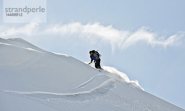 Ein Snowboarder zieht eine Kurve im Pulverschnee auf einem Bergrücken am Hatcher Pass  Southcentral  Alaska