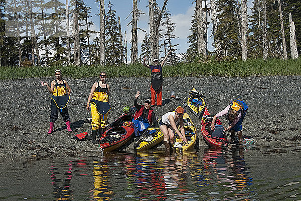 Gruppe von Kajakfahrerinnen  die sich in der Sonne vergnügen  während sie sich für eine Fahrt durch den Barry Arm  Kelly´s Cove  Chugach National Forest  Prince William Sound  Southcentral Alaska  Sommer  bereit machen