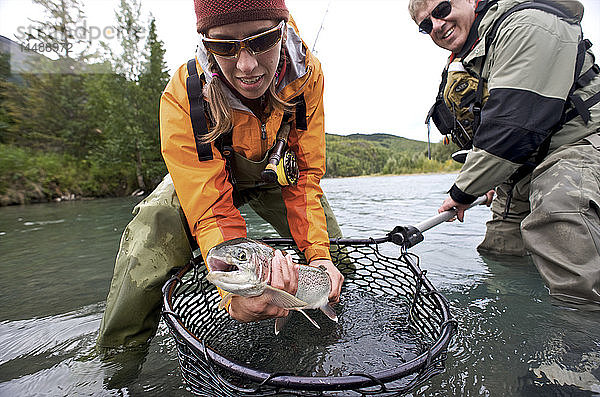 Mann und Frau halten eine Regenbogenforelle  die sie beim Fliegenfischen am oberen Kenai River auf der Kenai-Halbinsel in Süd-Zentral-Alaska im Herbst gefangen haben