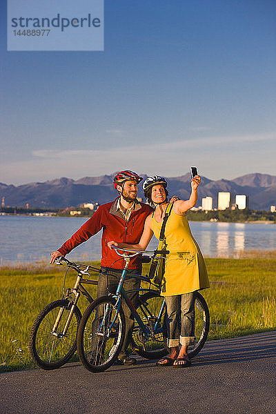 Radfahrer  die sich ausruhen und Selbstporträts entlang des Tony Knowles Coastal Trail mit der Skyline von Anchorage im Hintergrund machen  Southcentral Alaska