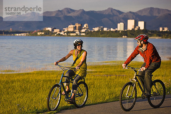 Fahrradfahrer auf dem Tony Knowles Coastal Trail mit der Skyline von Anchorage im Hintergrund  Southcentral Alaska