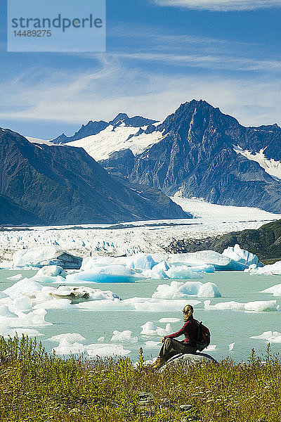 Eine Wanderin hält inne  um den Bear Glacier vom Ufer des Bear Glacier Lake im Kenai Fjords National Park  Kenai Peninsula  Southcentral Alaska  Sommer  zu betrachten.