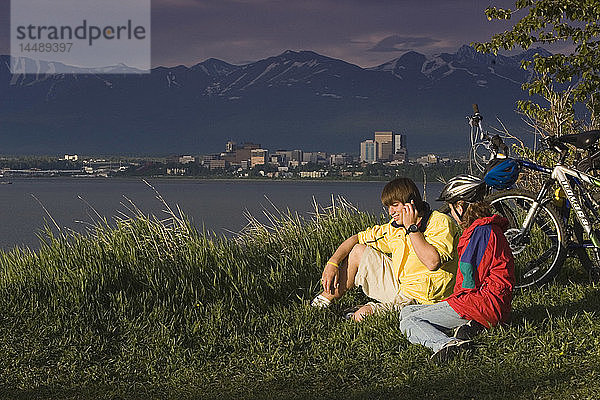 Junge und Mädchen telefonieren am Pt. Woronzof  während sie mit dem Fahrrad unterwegs sind Anchorage AK w/w/o bikes