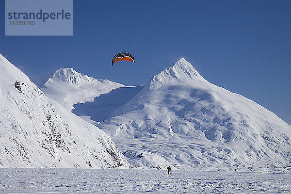 Ein Kite-Skifahrer fährt auf dem Portage-See mit den Chugach Mountains im Hintergrund  Southcentral  Alaska