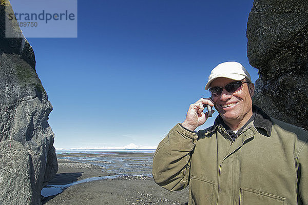 Mann mit Mobiltelefon neben großen Felsformationen  Clam Gulch  Kenai-Halbinsel  Southcentral Alaska