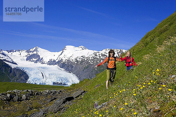 Mutter und Tochter wandern auf steilem  mit Wildblumen bedecktem Berghang Portage Pass Trail Chugach NF Alaska