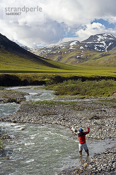 Blick auf einen Mann beim Fliegenfischen auf dem Chandalar River entlang des Dalton Highway im Sommer in Alaska