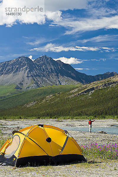 Mann beim Fliegenfischen am Dietrich River in der Brooks Range in der Nähe seines Zeltes und Campingplatzes im Sommer in Alaska