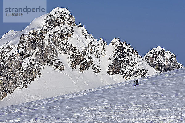 Alpinskifahrer beim Skifahren auf dem Juneau-Eisfeld und Rhino Peak im Hintergrund im Südosten Alaskas. Komposit