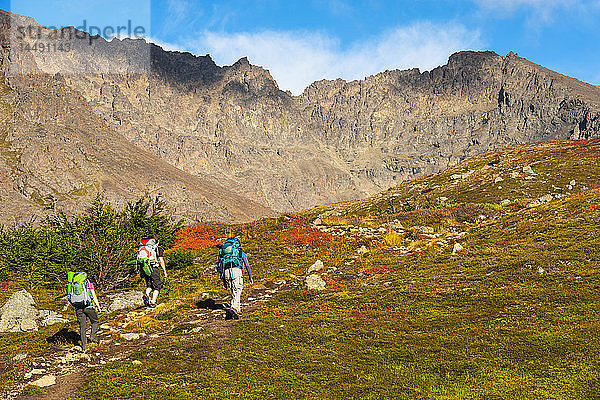 Drei Rucksacktouristen wandern an einem Herbsttag in Süd-Zentral-Alaska auf dem Hidden Lake Trail im Chugach State Park.