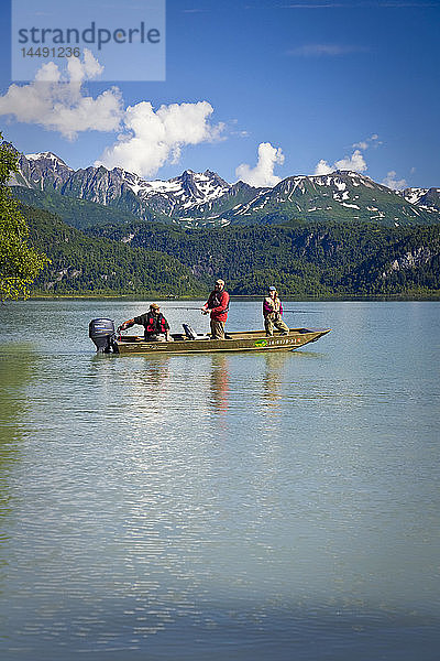 Ein Mann und eine Frau drehen Fische  während sie in einem Boot in den Big River Lakes in der Redoubt Bay State Critical Habitat Area in Süd-Zentral-Alaska im Sommer stehen