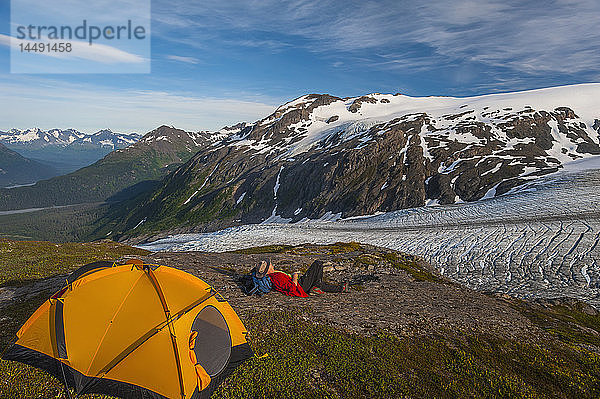 Rucksacktourist auf seinem Campingplatz auf einem Bergrücken mit Blick auf den Exit Glacier  Kenai Fjords National Park  Kenai Peninsula  Süd-Zentral-Alaska