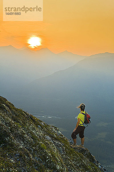 Wanderer am steilen Hang des Berges Alyeska  der den Sonnenuntergang über dem Girdwood Valley in Süd-Zentral-Alaska beobachtet