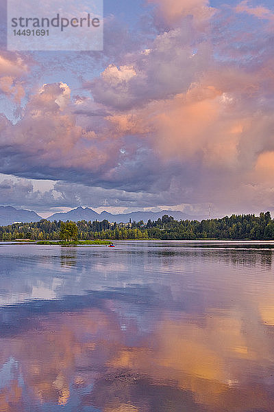 Paar beim Kajakfahren in der Westchester Lagoon mit rosa Wolken  die sich bei Sonnenuntergang im Wasser spiegeln  Downtown Anchorage  Southcentral Alaska  Sommer