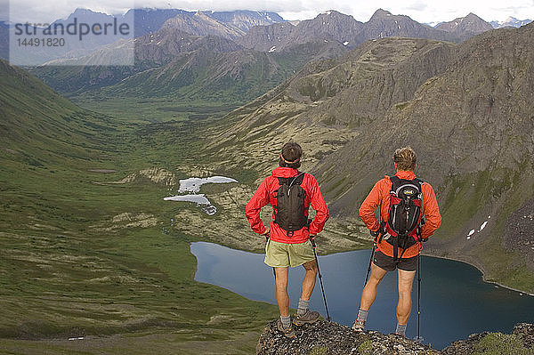 Zwei Wanderer betrachten einen Bergsee während eines Laufs durch die Chugach Mountains  einer zerklüfteten 32-Meilen-Verbindung zwischen den Gipfeln der Chugach Front Range in Southcentral Alaska Sommer