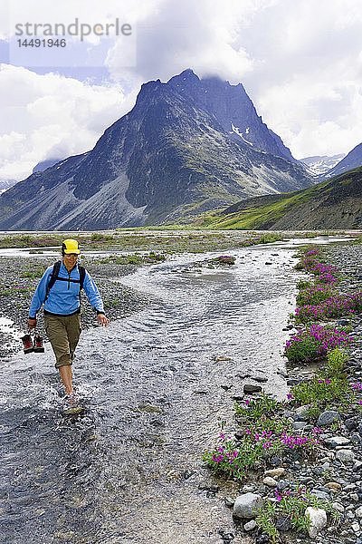 Wanderin watet durch einen Bach im Lake Clark National Park in der Nähe des Turquoise Lake AK Sommer