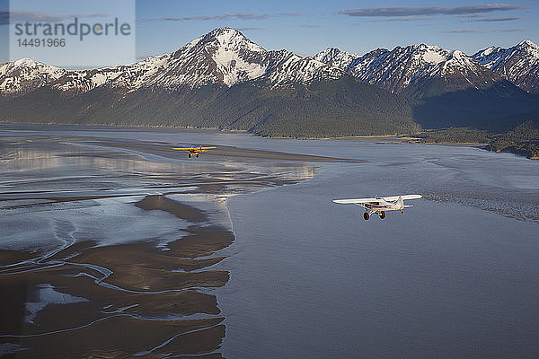 Super Cub Flugzeuge fliegen über Turnagain Arm mit Seward Highway und Chugach Mountains im Hintergrund  Southcentral Alaska