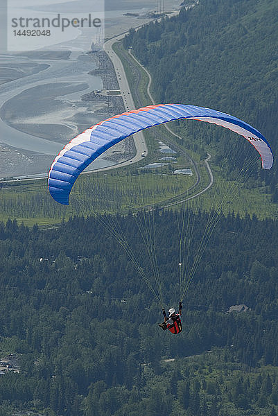 Ein Gleitschirmflieger schwebt über der Kulisse des Seward Highway und des Turnagain Arm in Süd-Zentral-Alaska