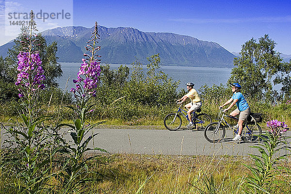 Ein Paar fährt zusammen Fahrrad auf dem Küstenpfad in der Nähe von Indian Alaska Turnagain Arm  SC Sommer.