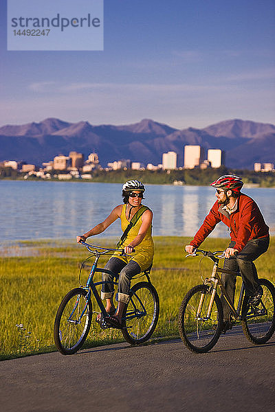 Fahrradfahrer auf dem Tony Knowles Coastal Trail mit der Skyline von Anchorage im Hintergrund  Southcentral Alaska