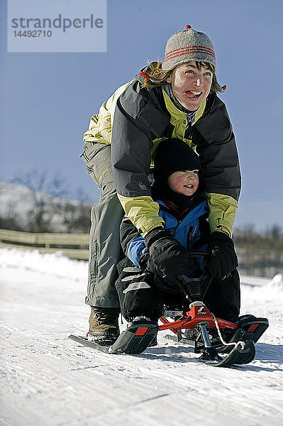 Mutter und Sohn beim Schlittenfahren im Schnee
