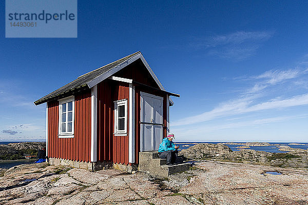 Frau sitzt vor einem kleinen Haus  Fjallbacka  Bohuslan  Schweden