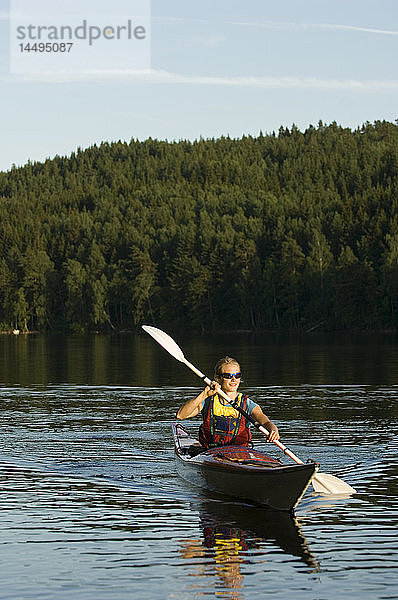 Eine Frau paddelt auf einem See  Schweden.