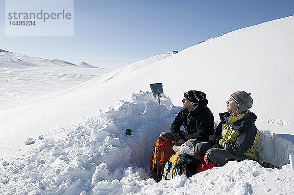 Ehepaar ruht auf einem schneebedeckten Hügel