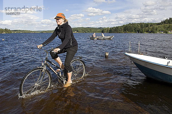 Eine Frau fährt auf einem Fahrrad im Wasser  Schweden.