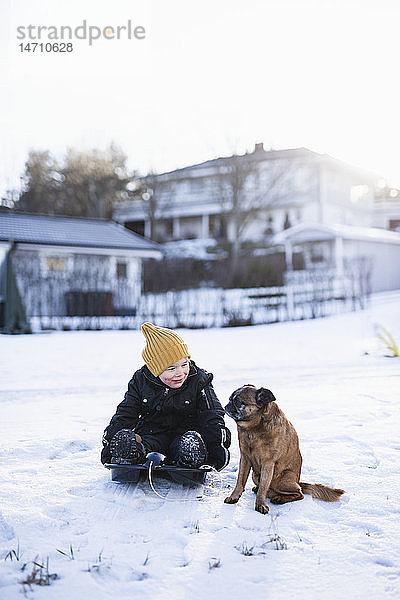 Junge sitzt mit Hund im Schnee