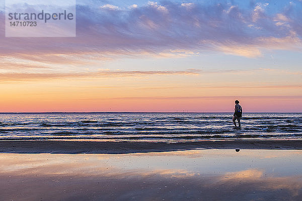 Silhouette einer Person am Strand bei Sonnenuntergang