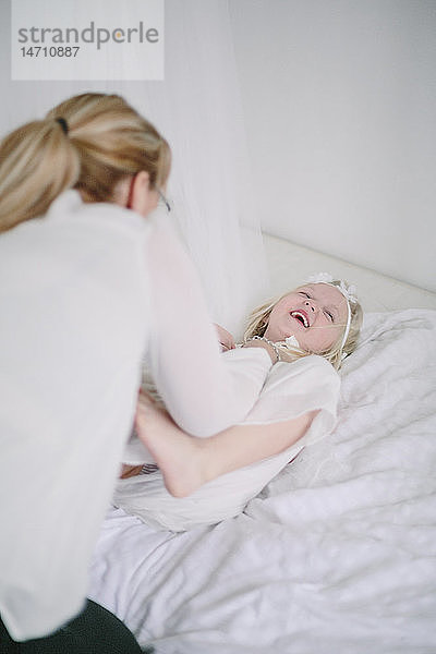 Blondes Mädchen spielt mit Mutter im Schlafzimmer