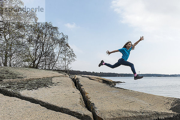 Mädchen springt am Seeufer