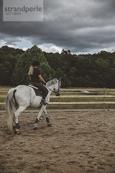 Frau reitet Pferd