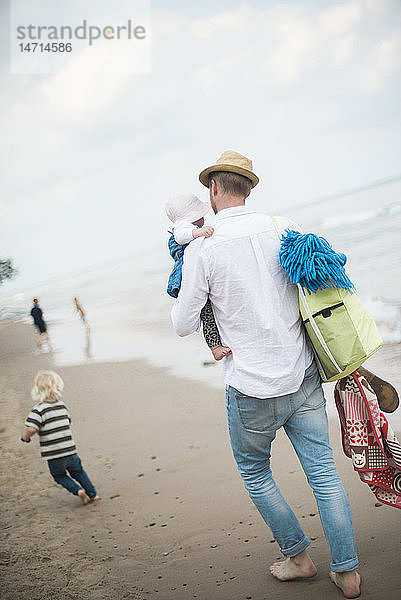 Vater mit Kindern beim Spaziergang am Strand