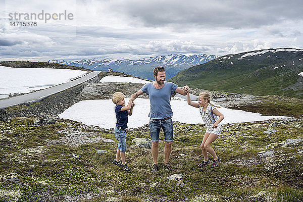 Vater spielt mit Kindern in den Bergen