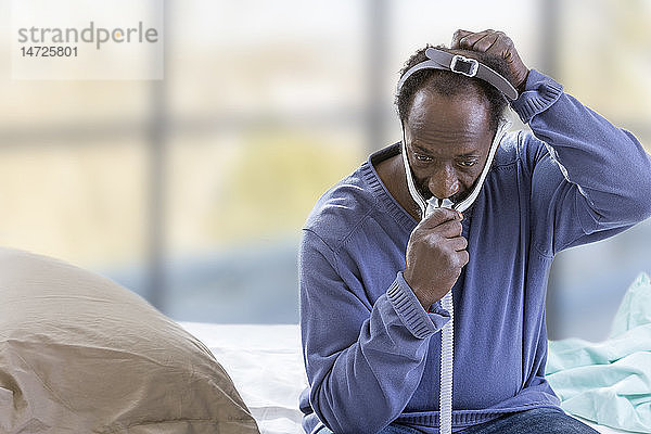 Mann mit einer CPAP-Maske (Continuous Positive Airway Pressure) zur Behandlung des Schlafapnoe-Syndroms.