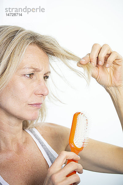 Frau betrachtet ihre gespaltenen Haarspitzen.