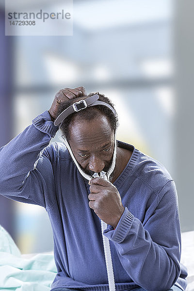 Mann mit einer CPAP-Maske (Continuous Positive Airway Pressure) zur Behandlung des Schlafapnoe-Syndroms.